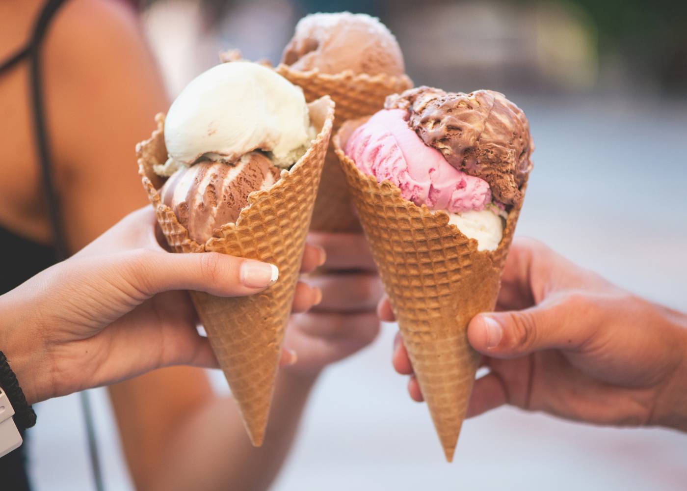 Zdjęcie lodów z bliska trzymanych przez trzy osoby