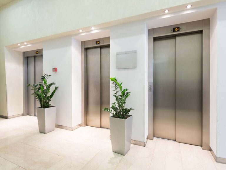 Korytarz z winfdami. Obrazek w artykule Winda w przeszłości i dziś. Ewolucja i stosowanie windy na przestrzeni lat