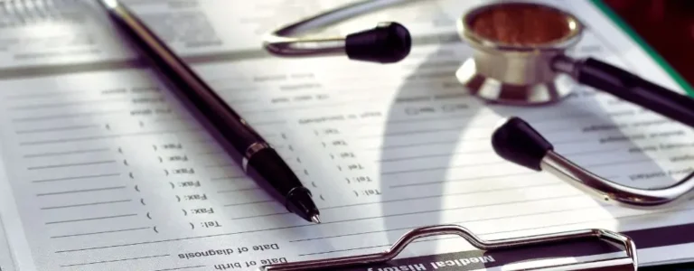 obrazek wyróżniający w artykule - Orzeczenie o niepełnosprawności. Na zdjęciu widać medyczną kartę pacjenta w formie drukowanego formularza, na której leży czarny długopis oraz stetoskop. Formularz zawiera sekcje do wypełnienia, jak „Date of diagnosis” i inne rubryki do wpisywania informacji o zdrowiu pacjenta. Stetoskop z metalową głowicą i czarnym przewodem leży obok, co sugeruje kontekst medyczny i odnosi się do procedur związanych z dokumentacją zdrowotną, diagnozami lub badaniami lekarskimi. Całość wskazuje na tematykę zdrowia i formalności medycznych.